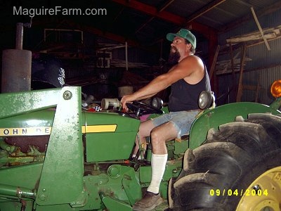 Close up - Bob inside a barn on a green John Deere Tractor