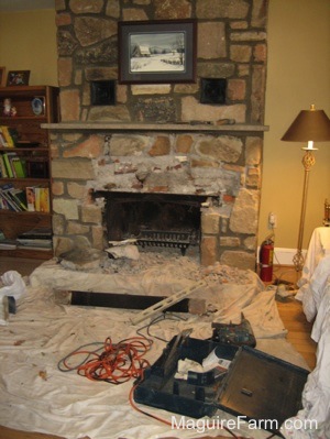The Stone over top of the fireplace opening is being chipped away. There is a drop cloth and tools all over the area.