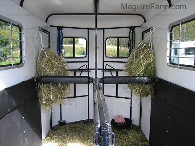 On the inside of a trailer is two bags of hay hanging from each side of the walls
