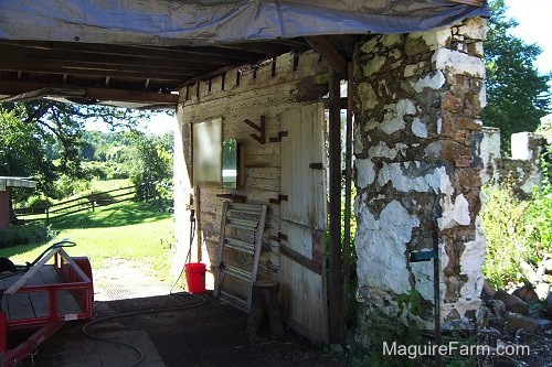 The stone walls of an old barn that burned down with one section of roof remaining